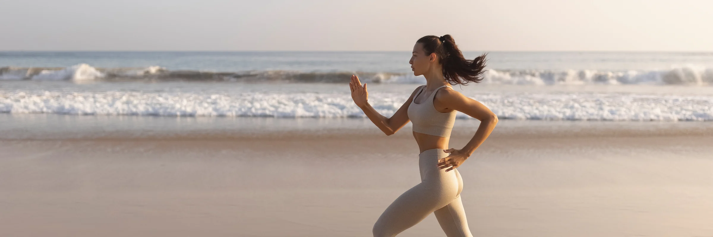 Woman running along the beach at sunrise